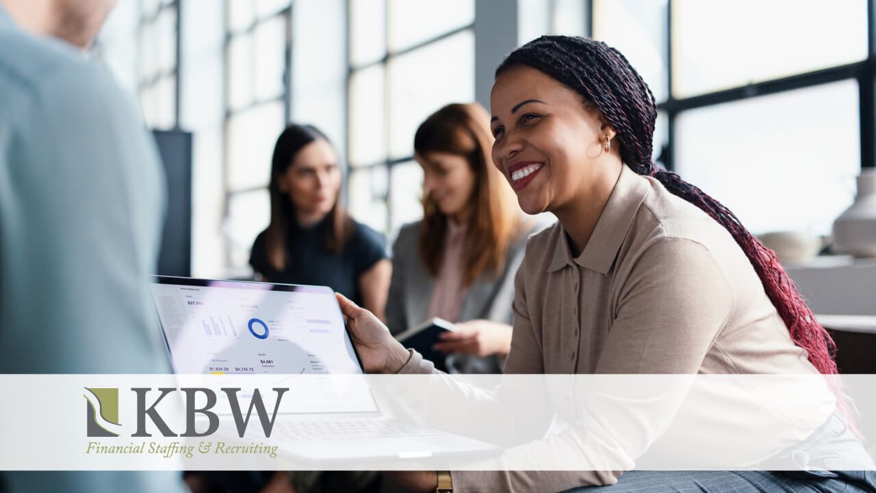 In an office setting, a woman smiles as she sits among other people working together.