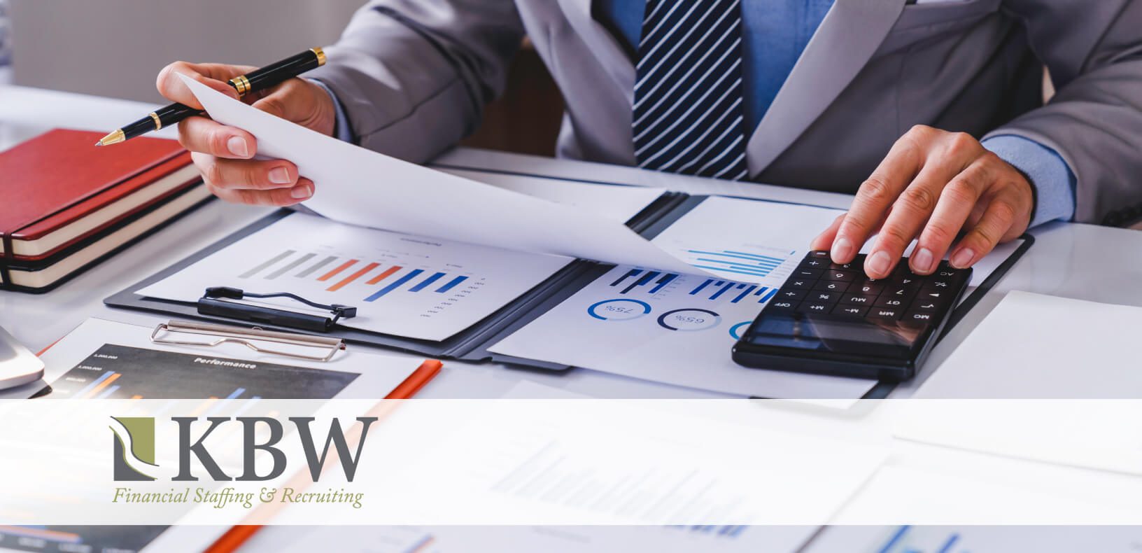 a man in a suit sits at a desk with a calculator and paperwork with bar charts on them